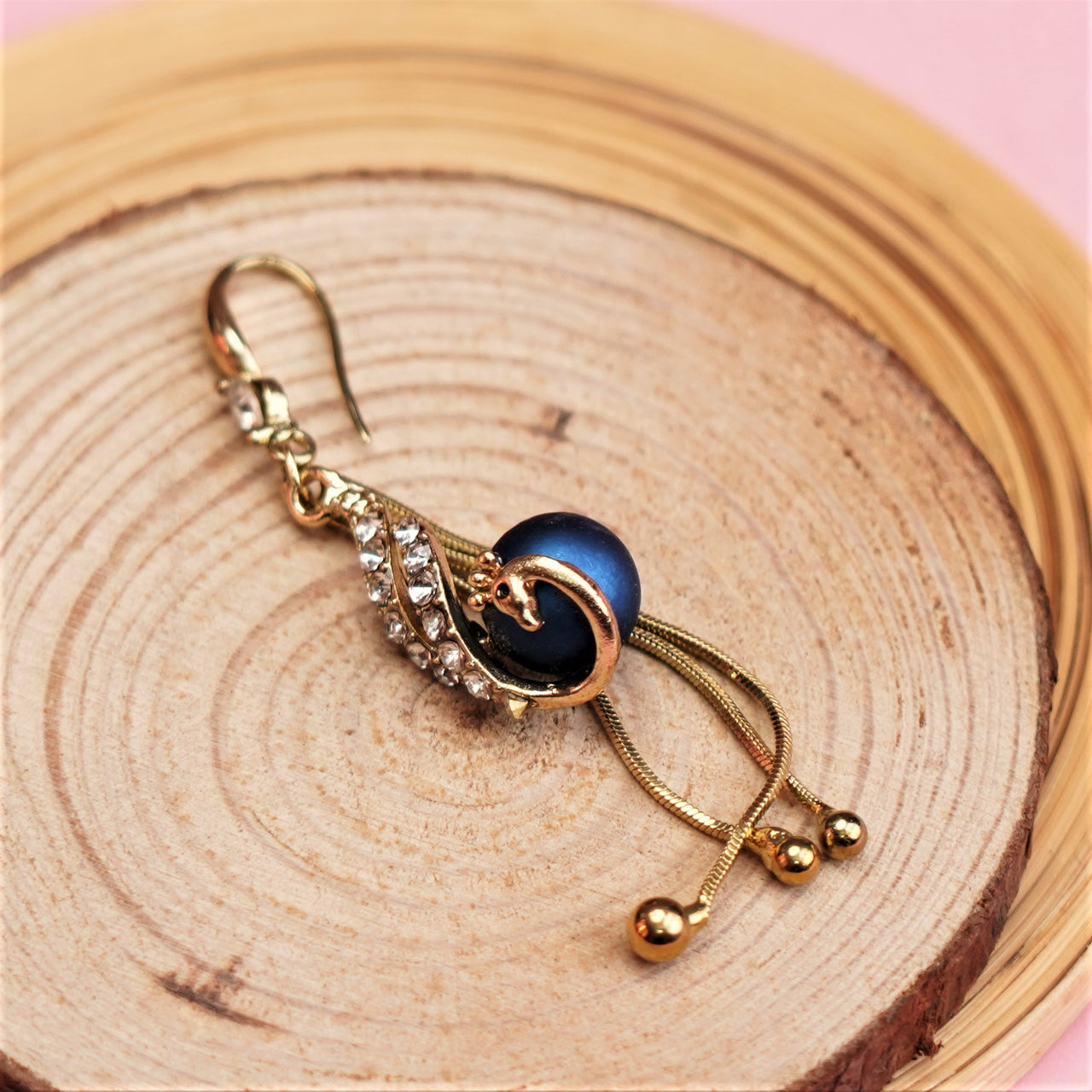 A peacock design ear ring on a wooden props. 