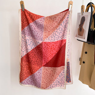 Colorful patterned scarf hanging on a rack with a coat and photo frame in the background.