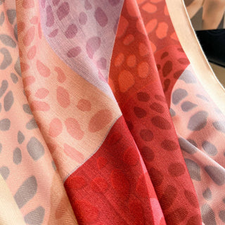 Close-up of a fabric with a patterned design, featuring shades of red, pink, and beige.