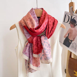 Colorful patterned scarf on a hanger with a magazine and handbag in the background.
