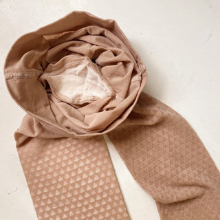 Folded beige fabric with a textured pattern on a light background