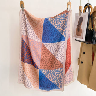 Colorful patterned scarf on a hanger with a coat and purse in the background