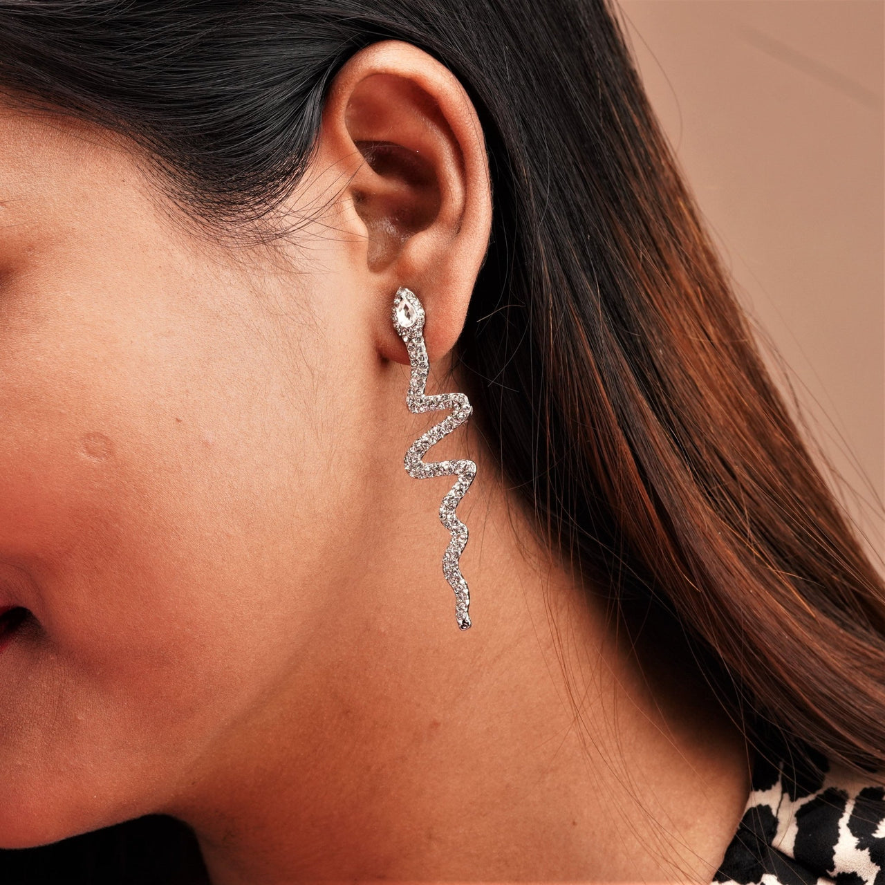A snake design earring with stone hanging on ear