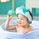 A baby is playing with a ball wearing a blue color shower cap 