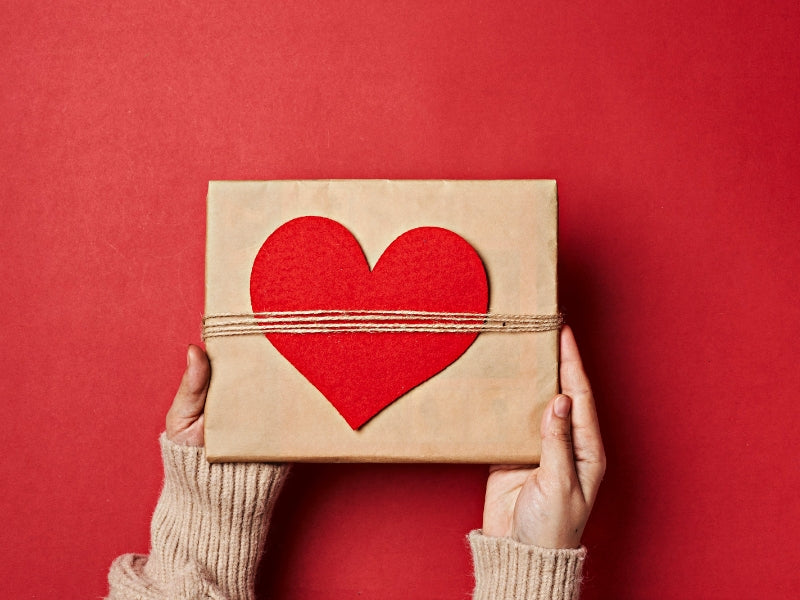 category picture for gifts. A pair of hand holding a gift with heart shape paper cut.