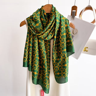 Green and gold patterned scarf on a wooden hanger against a white background