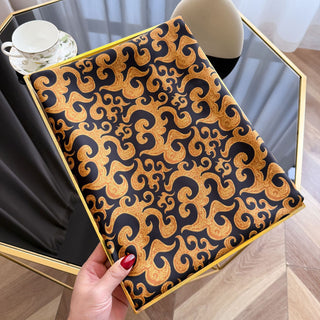 Decorative tray with gold and black pattern held by a hand on a wooden floor.