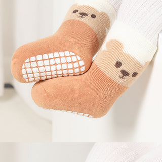 Pair of baby socks with bear faces and textured sole on a light background