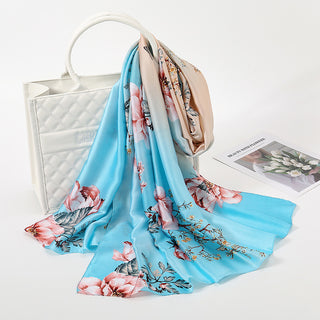 Floral scarf on a white surface with a handbag and magazine in the background