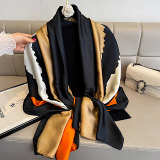 Colorful scarf with black, gold, and orange pattern draped over a sofa.