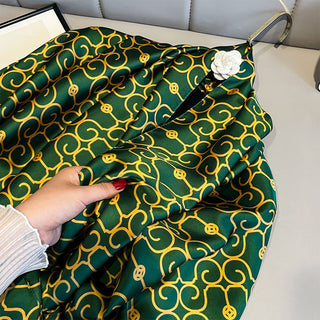 Green fabric with yellow patterns held by a hand on a light-colored surface