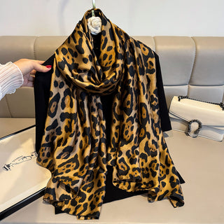 Leopard print scarf draped over a black garment on a white surface.