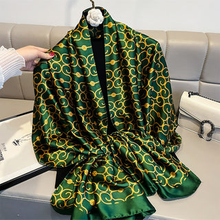 Green and gold patterned scarf draped over a chair with a hand holding it.