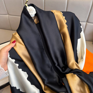 Black and gold scarf draped over a chair with a hand holding it.