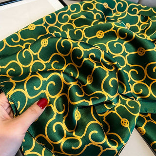 Green fabric with gold patterns held by a hand