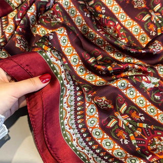 Close-up of a hand holding a piece of patterned fabric with intricate designs.