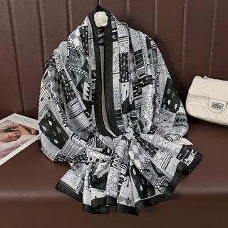 Black and white patterned scarf draped over a chair with a magazine and handbag in the background.