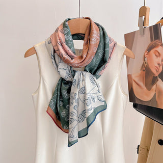 Colorful patterned scarf draped over a white garment on a wooden hanger against a light background.