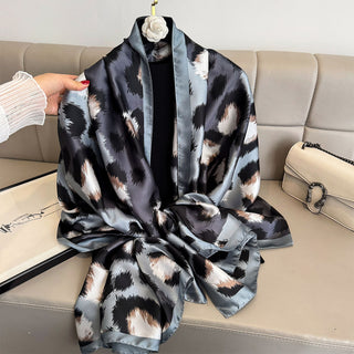 Person holding a patterned scarf on a beige couch with a handbag in the background
