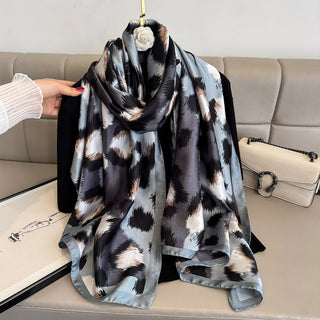 Patterned scarf draped over a sofa with a hand holding it