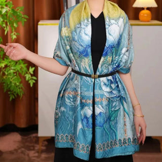 Woman wearing a blue patterned jacket indoors with a plant and lamp in the background
