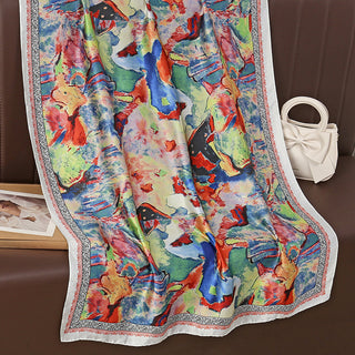 Colorful scarf with animal print on a brown surface, next to a white handbag.