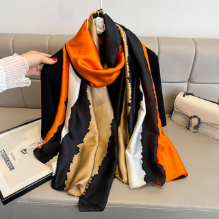 Multicolored scarf draped over a couch with a hand holding it