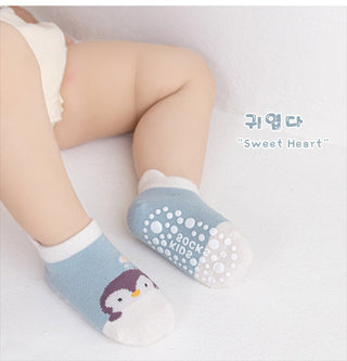 Baby's legs wearing blue socks with penguin design on a white background