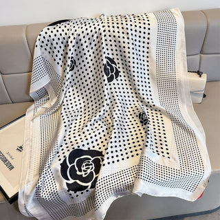 Black and white patterned scarf with floral designs draped over a sofa.
