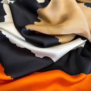 Close-up of fabric with black, beige, white, and orange colors.