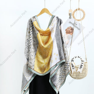 A silk scarf with a geometric pattern featuring shades of gray, yellow, and white, displayed on a wooden hanger.